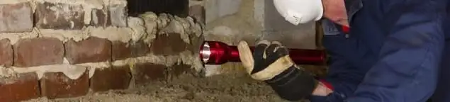 Pest control technician inspecting a crawl space for ant activity and entry points in Akron, OH