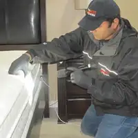 Bed bug inspection technician checking a mattress and bed frame for signs of infestation in Akron, OH