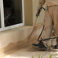 General pest control technician spraying exterior perimeter around a home in Akron, OH