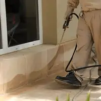 General pest control technician spraying exterior perimeter around a home in Akron, OH