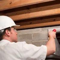 Termite inspection technician checking a basement wall and framing for termite activity in Akron, OH
