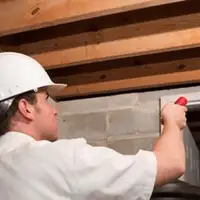 Termite inspection technician checking a basement wall and framing for termite activity in Akron, OH